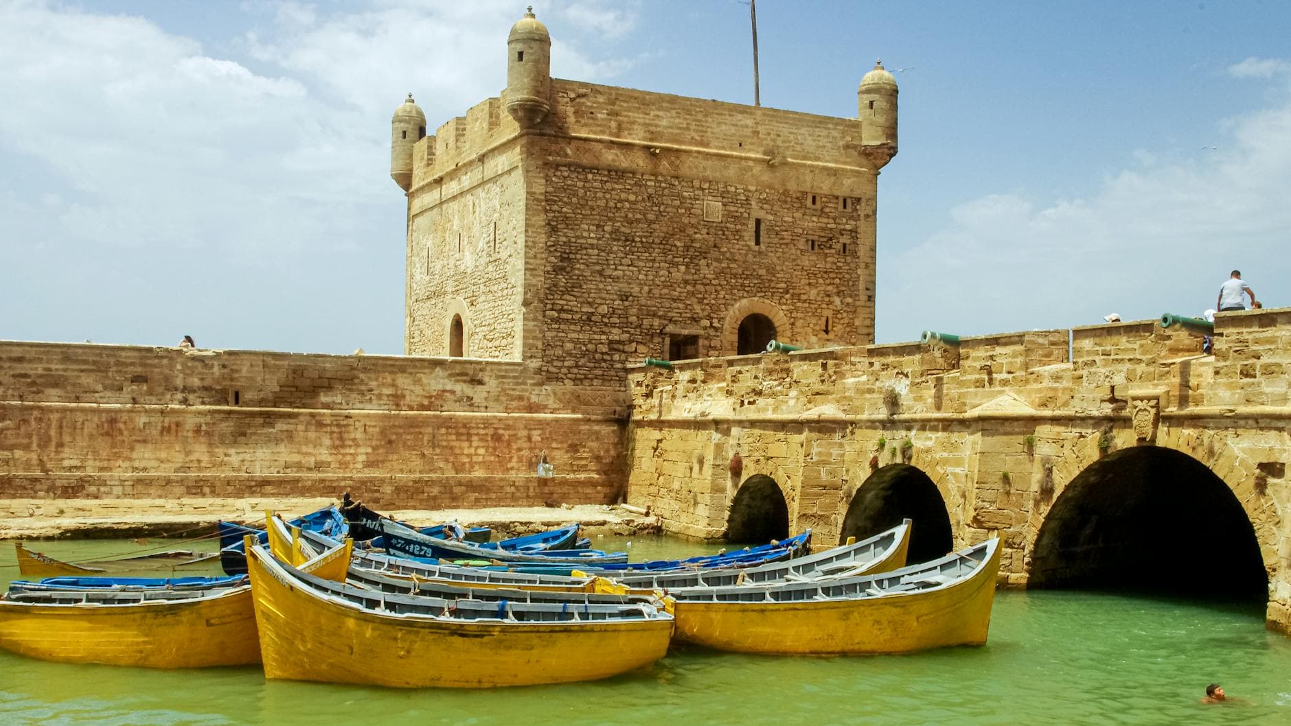 A stunning view of the ancient fortress and colorful boats moored in the port of Essaouira, Morocco.