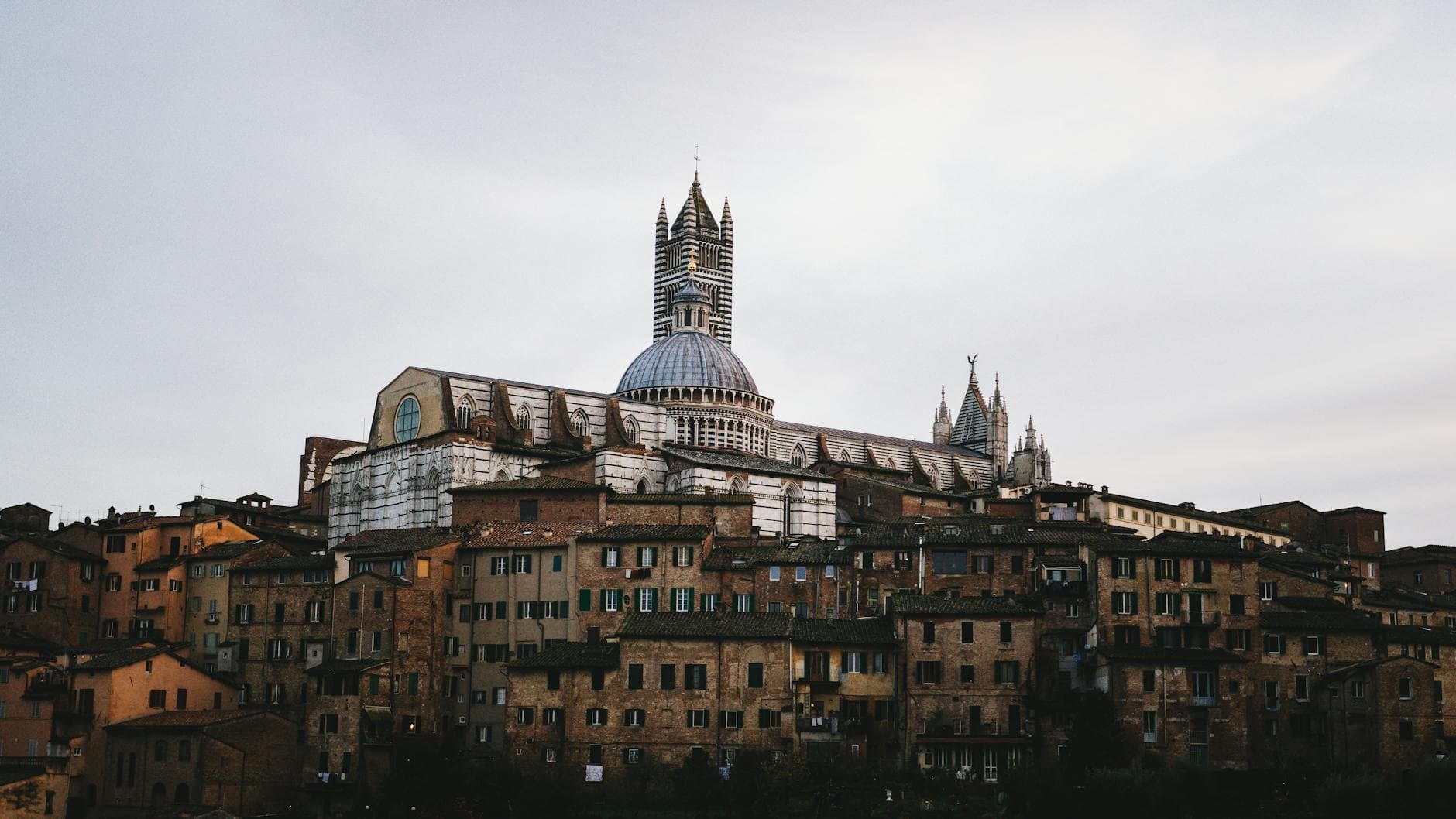 A picturesque view of Siena Cathedral towering above the historic buildings of Siena, Italy.
