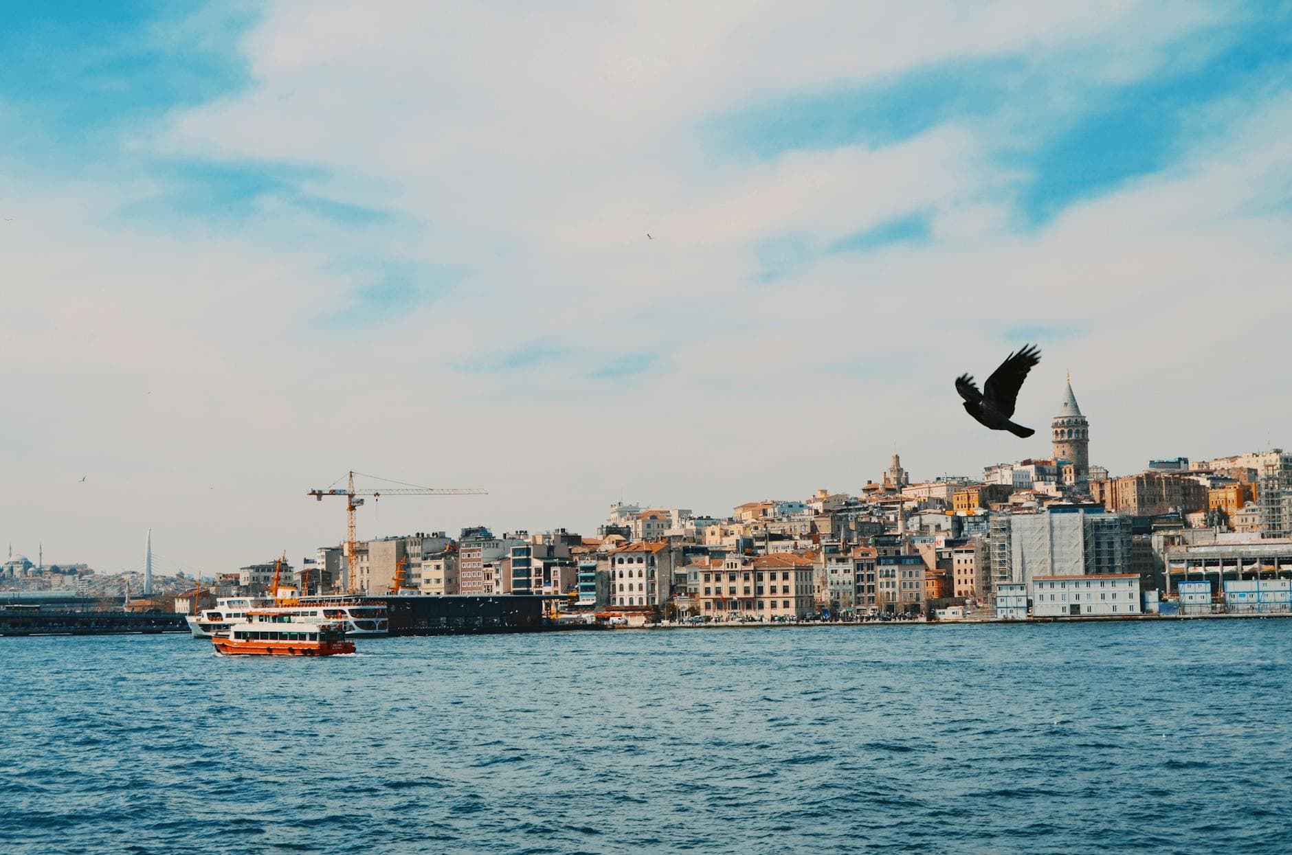 A scenic view of Istanbul's Bosphorus with a ferry and Galata Tower in the background, capturing urban life.
