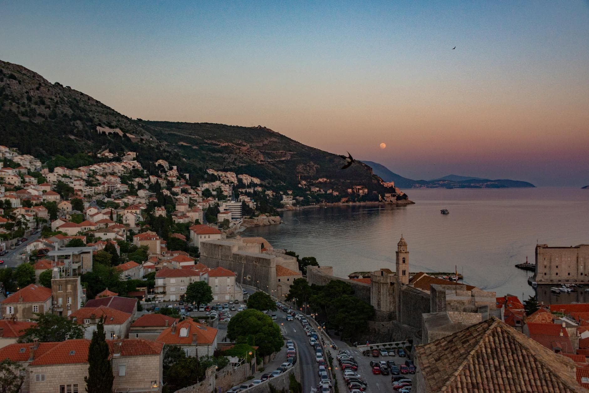 Stunning aerial capture of Dubrovnik's coastal cityscape at sunset, showcasing its historic architecture and Adriatic seascape.