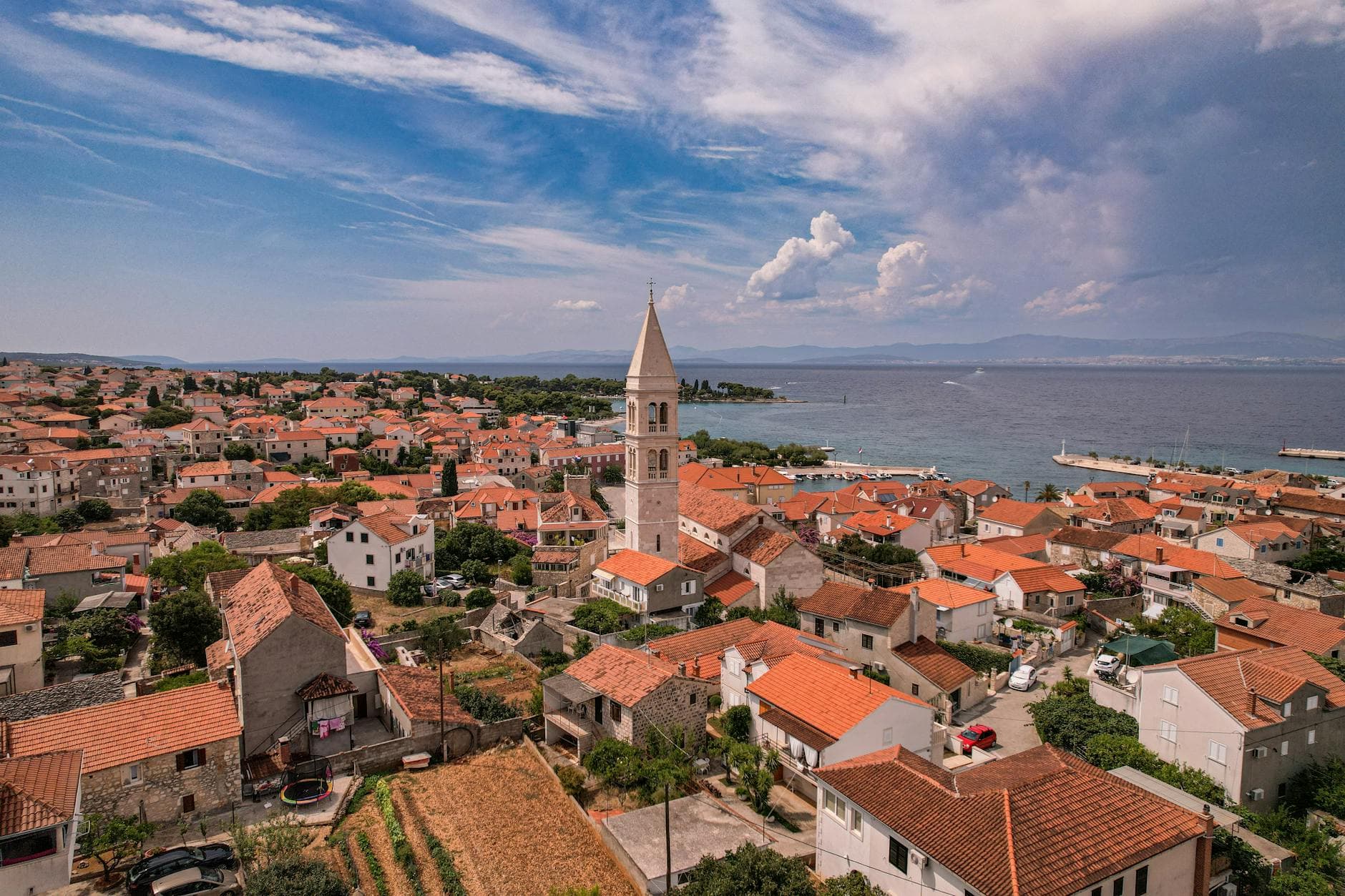 Scenic aerial view of a European coastal town with a prominent historic church tower by the sea.