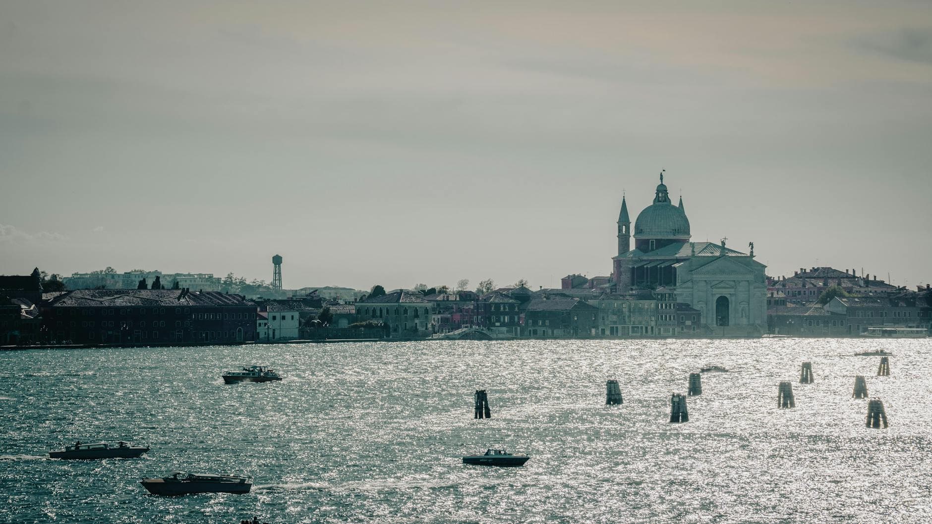 Dramatic skyline of Venice featuring boats on the water and a historic basilica.