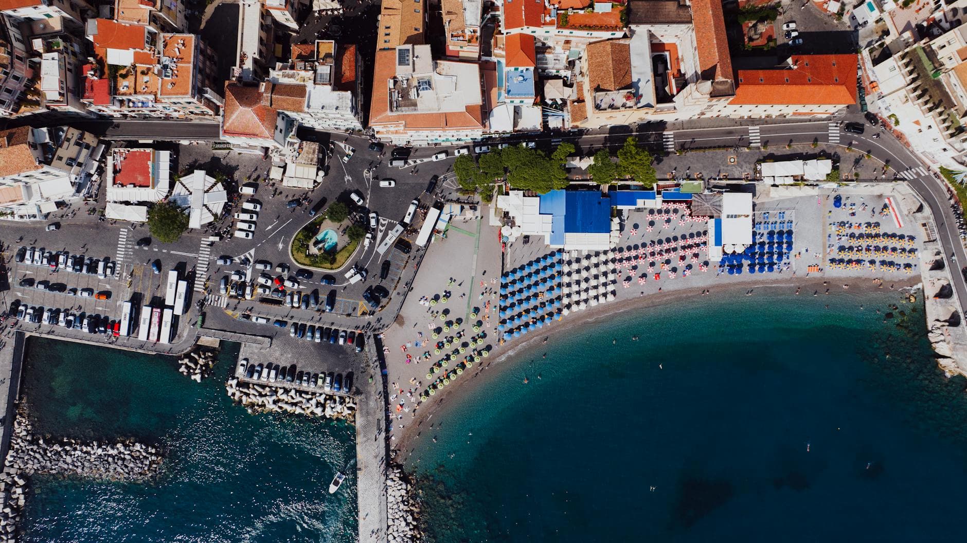 Stunning aerial view of Amalfi's beach, colorful umbrellas, and historic town buildings.