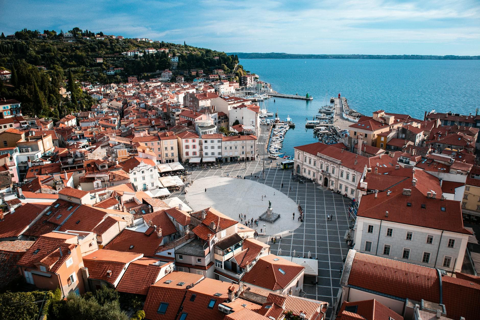 Stunning aerial view of Piran's charming square, red rooftops, and harbor along the Adriatic coast in Slovenia.
