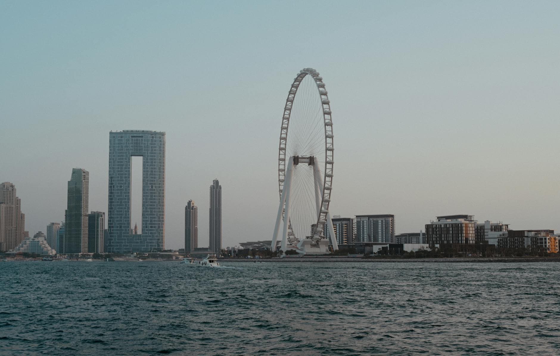 Scenic view of the Dubai skyline featuring Ain Dubai, skyscrapers, and modern architecture by the waterfront.