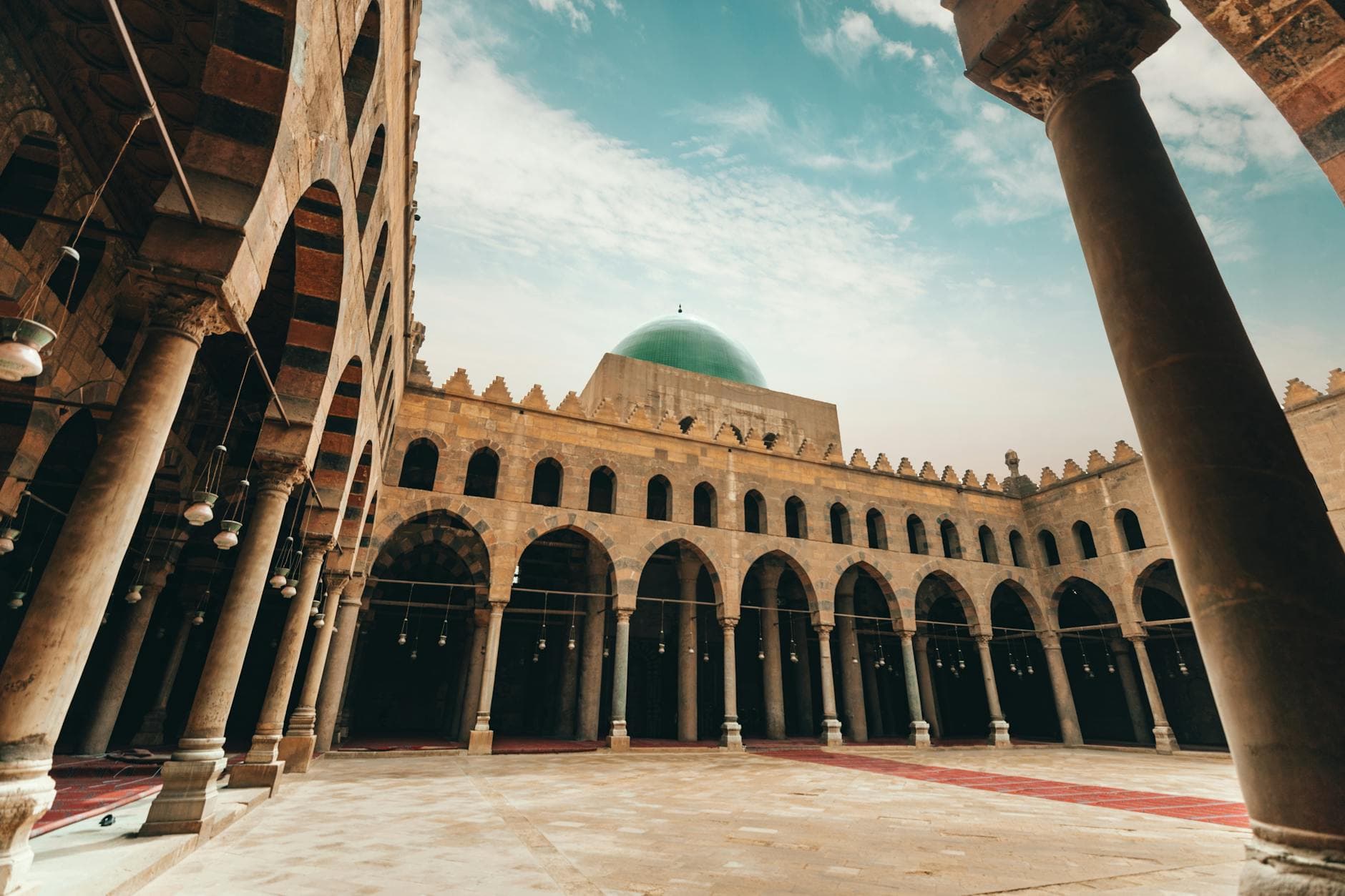 View of a historic mosque's courtyard with domed architecture under a blue sky in Cairo, Egypt.