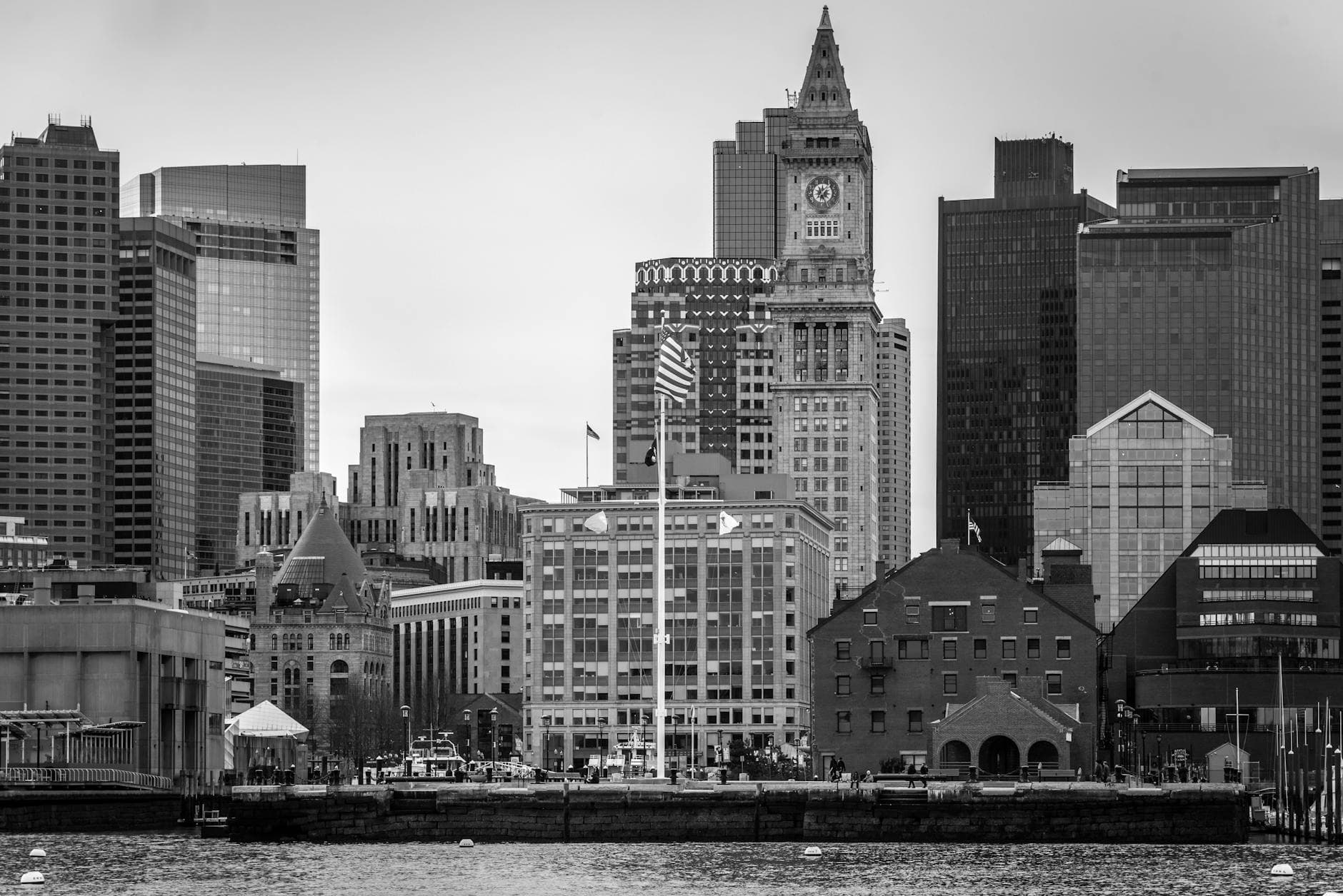 Black and white view of Boston skyline featuring the Custom House Tower from the waterfront.