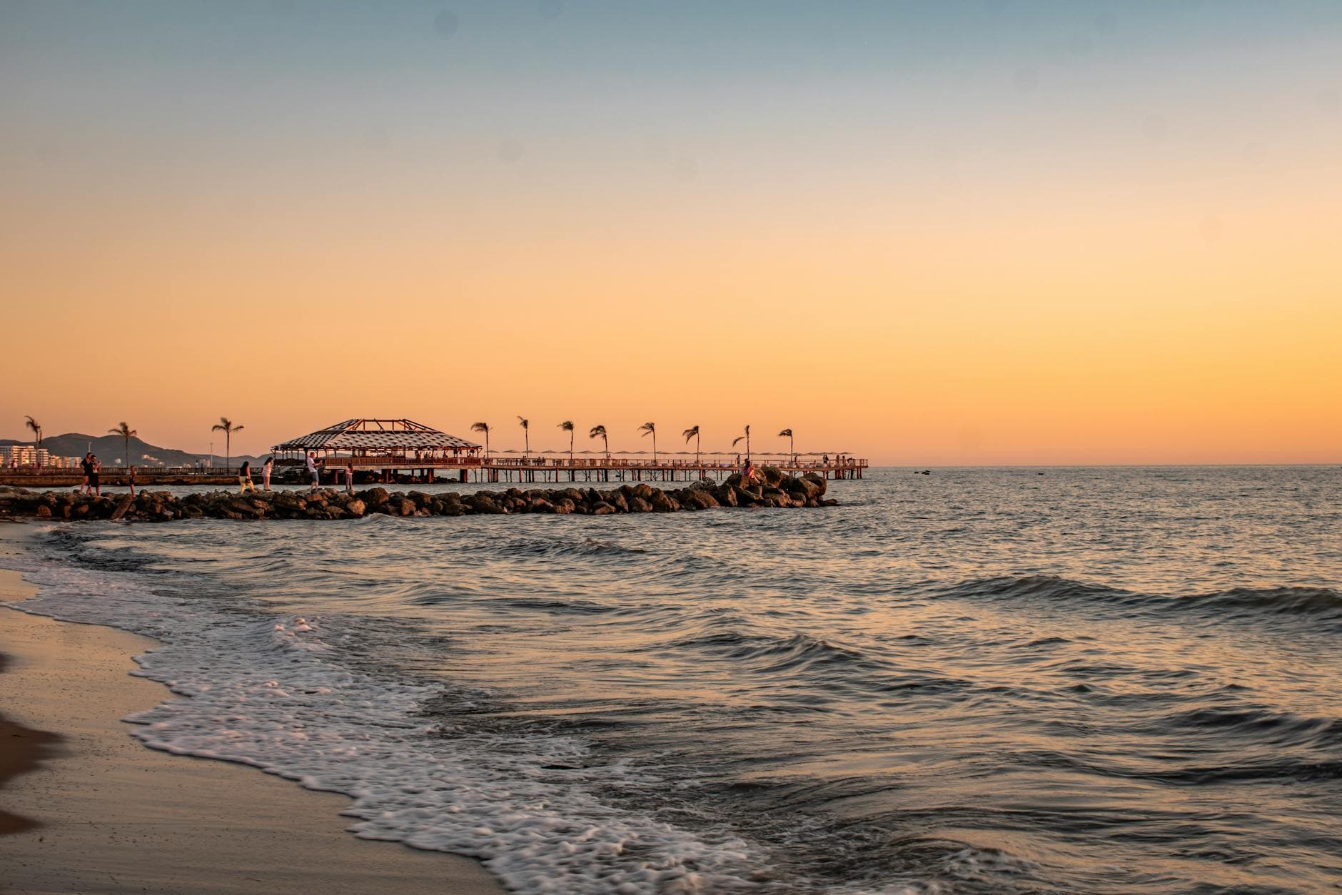 A serene view of a sunset over Golem Beach, Albania, highlighting calm seas and a vibrant sky.