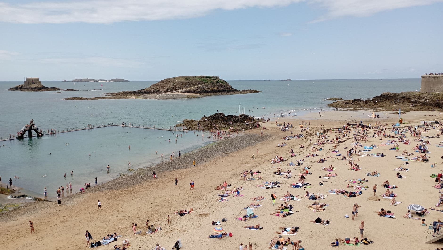 A sunny day at Saint-Malo beach with tourists enjoying the seaside views.