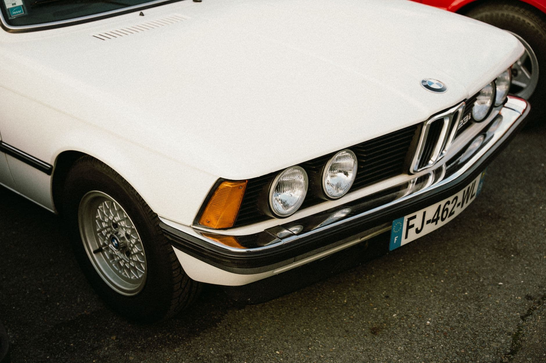 Close-up of a vintage white car's front, captured in Montigny-le-Bretonneux, France.