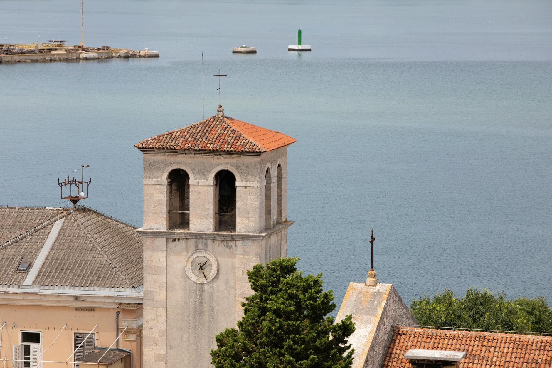 A picturesque view of a historic bell tower and rooftop by the Adriatic Sea in Pula, Croatia.