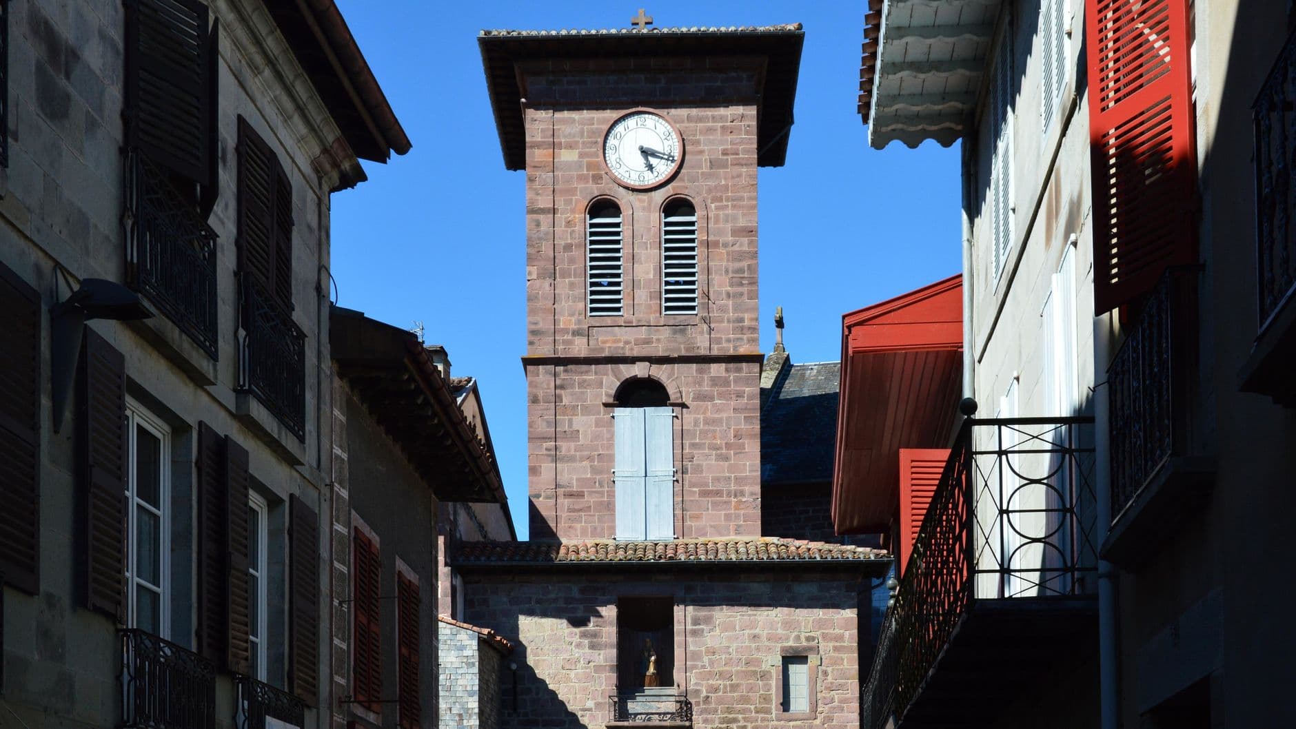 Charming view of the historic clock tower in Saint-Jean-Pied-de-Port, France, under a clear blue sky.