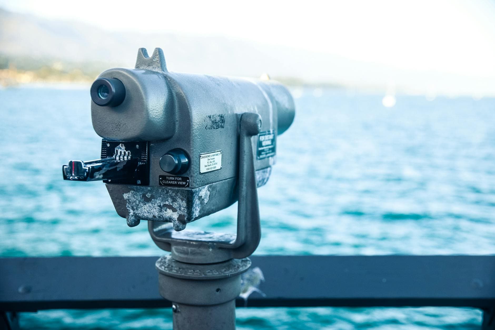 Coin-operated binoculars on a pier with scenic view of Santa Barbara coastline and ocean.