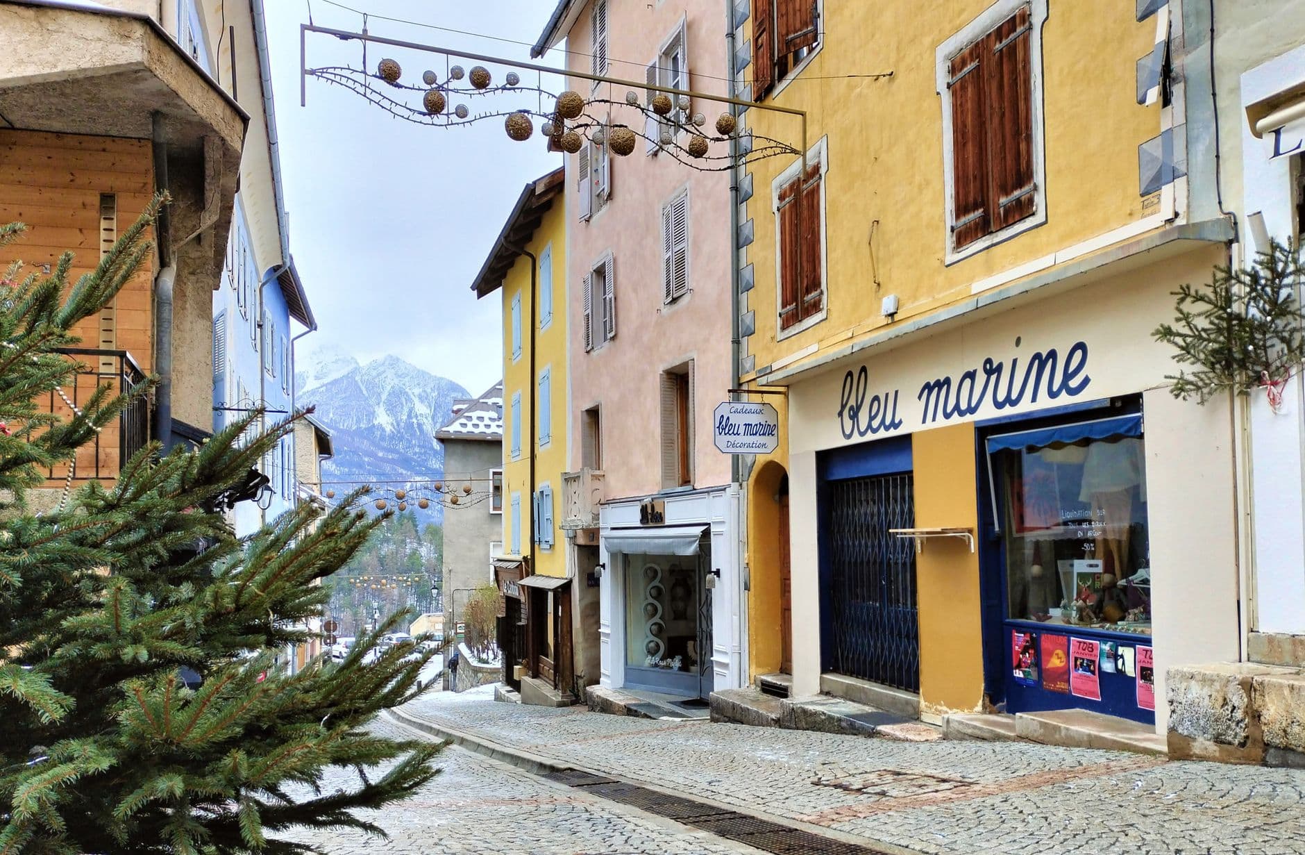 Picturesque street in Briançon, France with colorful buildings and snowy mountain backdrop.
