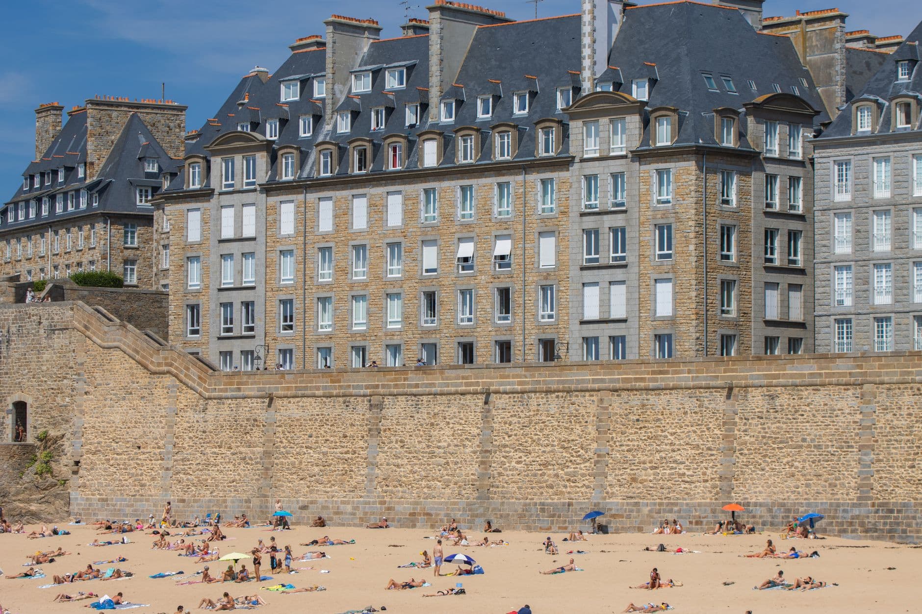 View of historic buildings and beachgoers in Saint-Malo, Brittany, France.